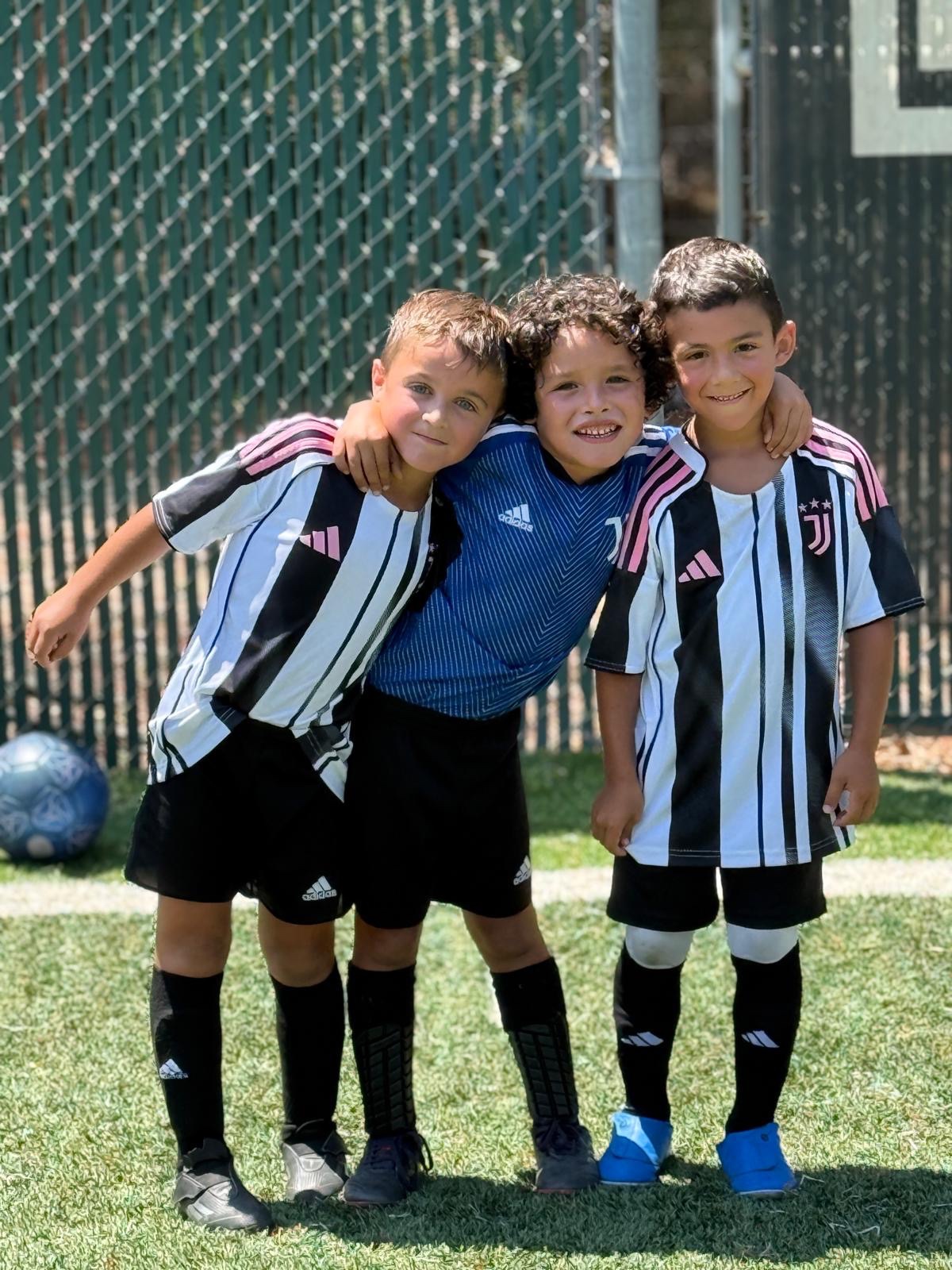 Three young Juventus Academy Phoenix players posing on the field