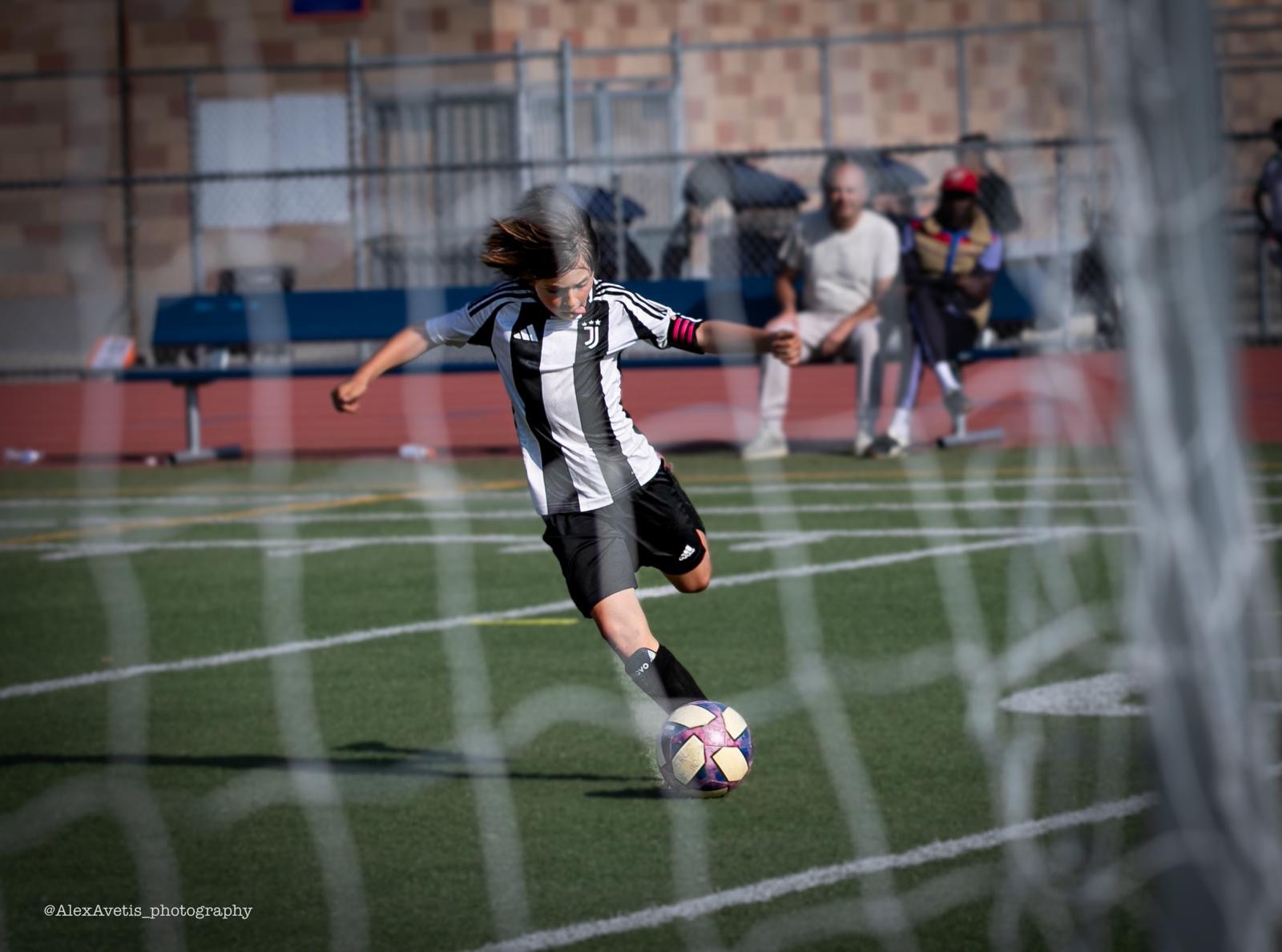 Juventus Academy Phoenix player taking a shot through the goal net